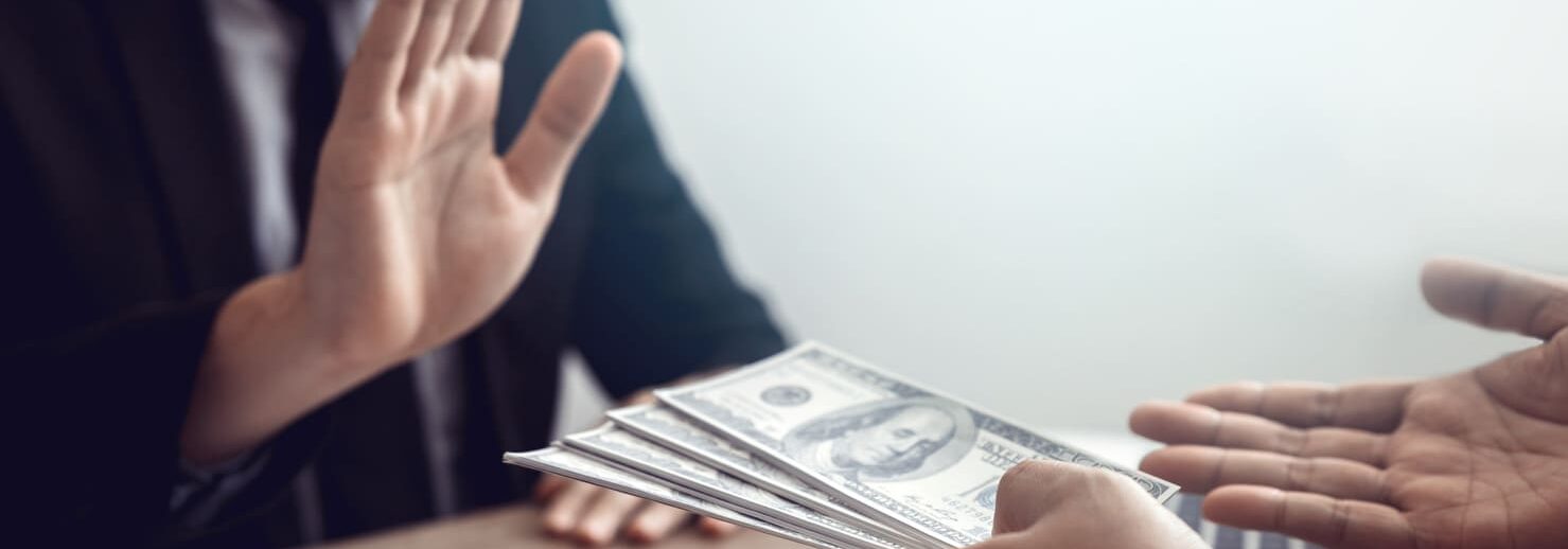 Geld wird angeboten an Schreibtisch, ablehnende Hand